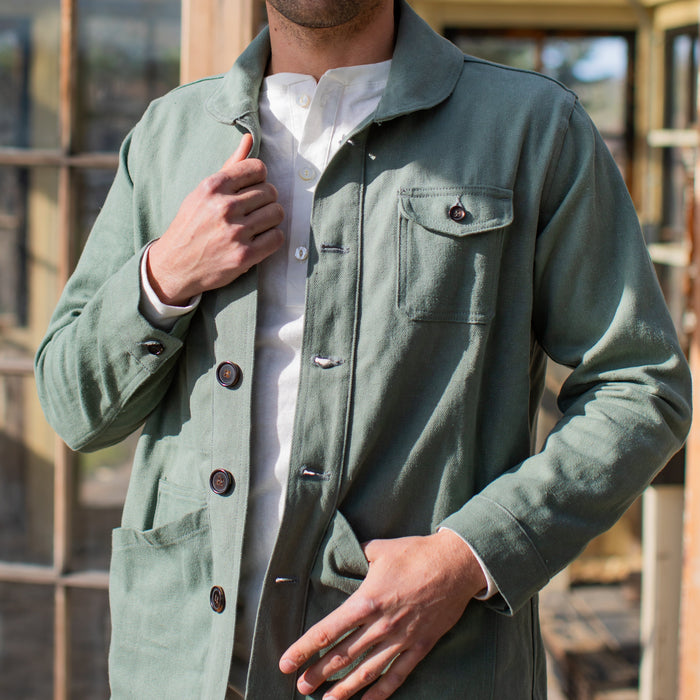 Man wearing a green jacket standing in front of a rustic metal structure