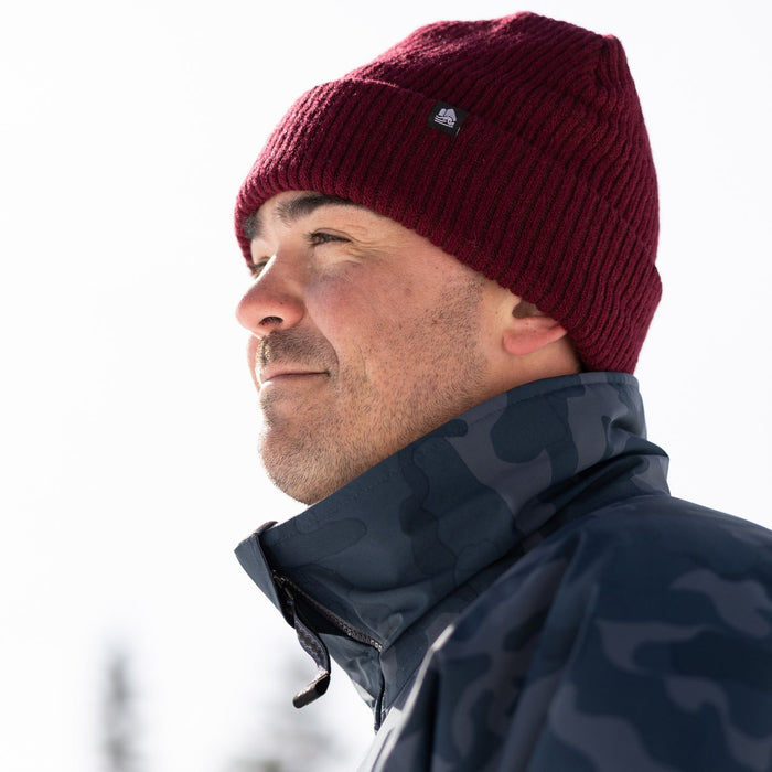 Man wearing a red beanie and dark jacket against a white background