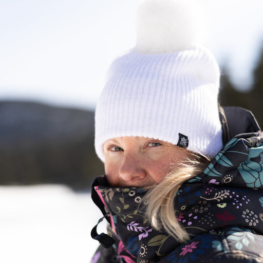 Person wearing a colorful winter coat and white beanie with a blurred background