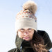 Person wearing a patterned beanie with a pom-pom against a clear blue sky.