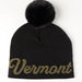 Black beanie with 'Vermont' text and black pom-pom on a white background