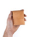Hand holding a small brown leather wallet against a white background