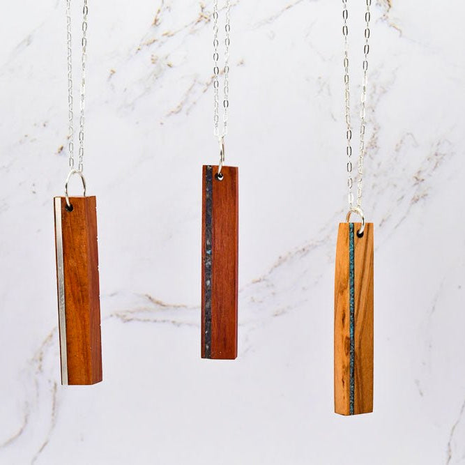 Three wooden pendant necklaces on a marble background