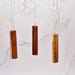 Three wooden pendant necklaces on silver chains against a marble background