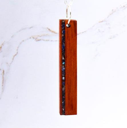 Wooden pendant with embedded material on a white marble background