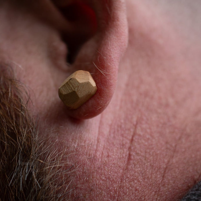Close-up of a person wearing a gold hexagonal earring.