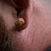 Close-up of a person wearing a gold hexagonal earring.