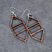 Pair of geometric copper earrings on a gray stone surface