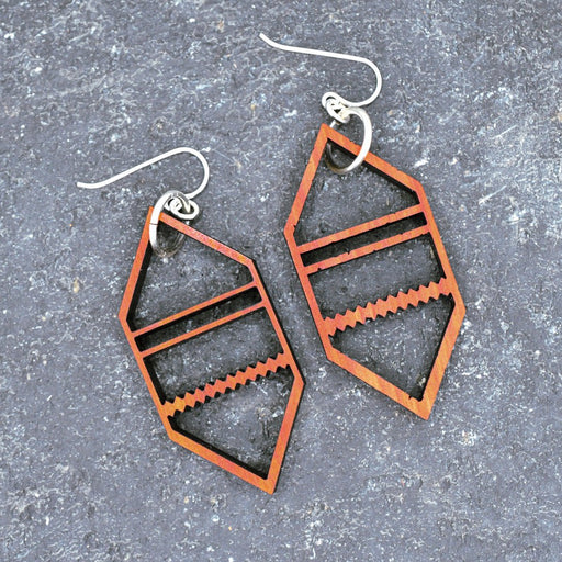 Geometric earrings on a textured gray surface