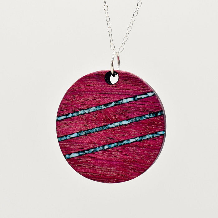 Round pink pendant with blue stripes on a white background
