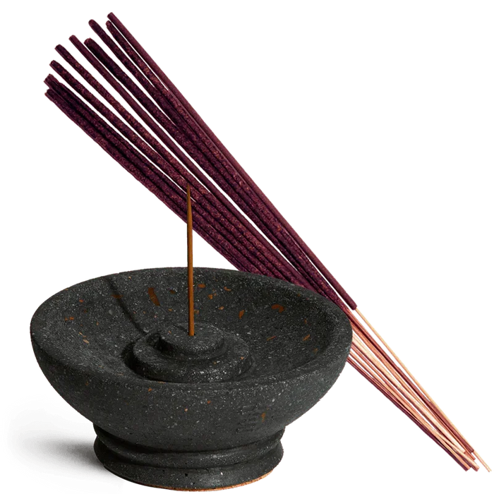 Black incense burner with a single incense stick and purple incense sticks on a white background
