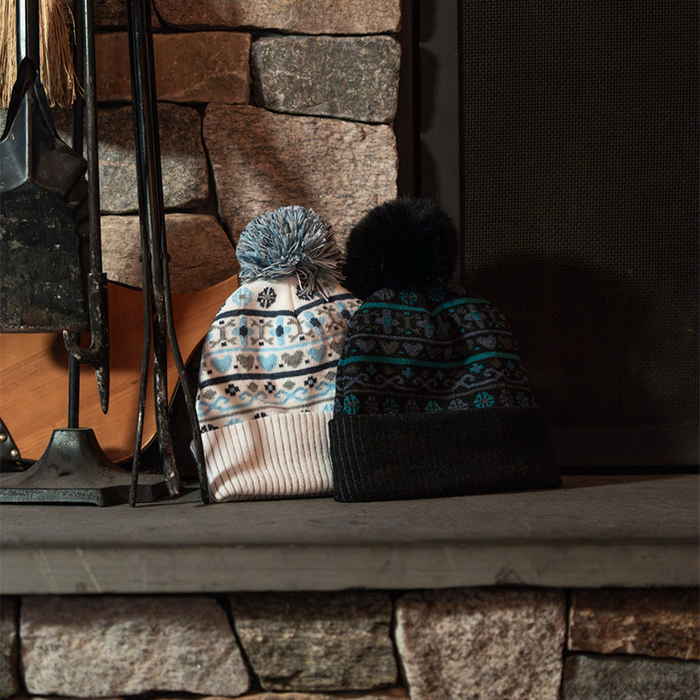 Two knit hats on a stone fireplace mantle.