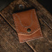 Brown leather wallet with button closure on a wooden surface